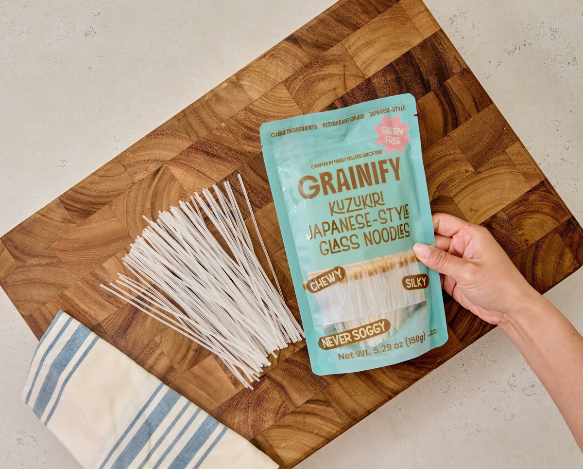 Hand holding the Grainify Kuzukiri pouch over dried glass noodles on a cutting board
