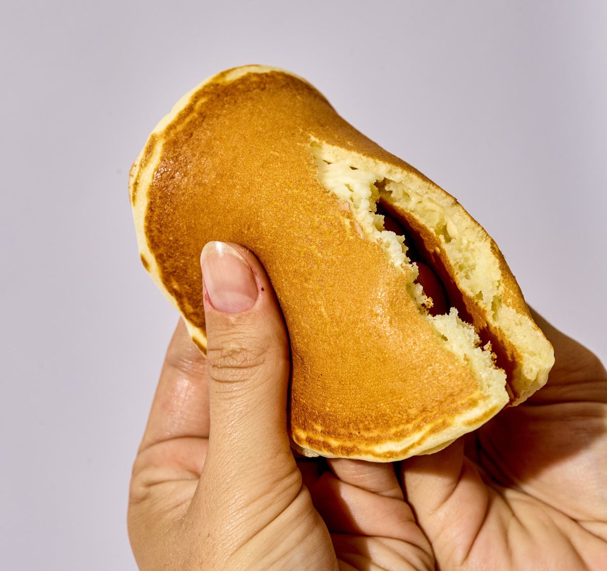 Hand holding a torn mochi pancake showing the chewy centre